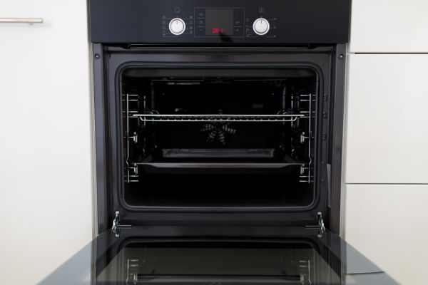 a clen oven with the door opened , it has two shelves and white knobs