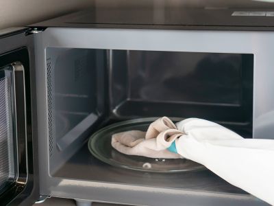 microwave with the door opened, there is a cloth for cleaning laying on the turntable inside.