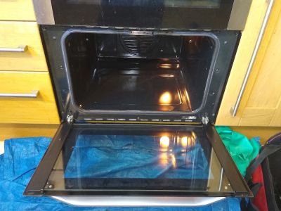 a oven with the door fully opened, it is clean, there is a blue cloth on the floor under the oven door