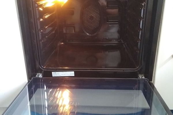 The oven is open and it is shiny clean, the oven light is on