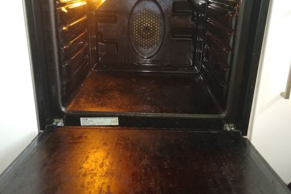 Inside the cavity of a dirty oven, the door is open and you can see lots of grease and grime