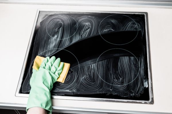hand in a rubber glove cleaning a hob with a sponge