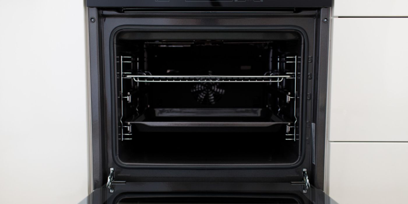 a clen oven with the door opened , it has two shelves and white knobs