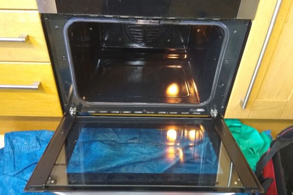 The oven is open and it is shiny clean, the oven light is on