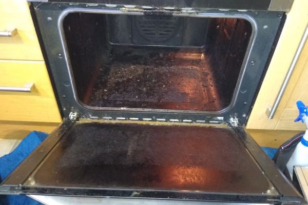 Inside the cavity of a dirty oven, the door is open and you can see lots of grease and grime