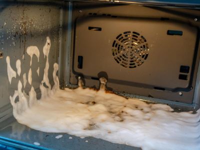 inside an open oven there is soapy liquid suggesting an oven being cleaned