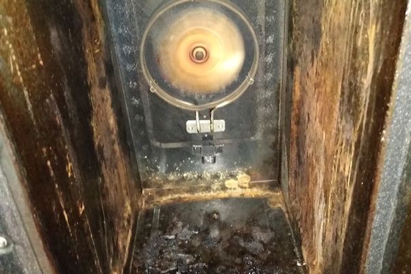 Inside the cavity of a dirty oven, the door is open and you can see lots of grease and grime