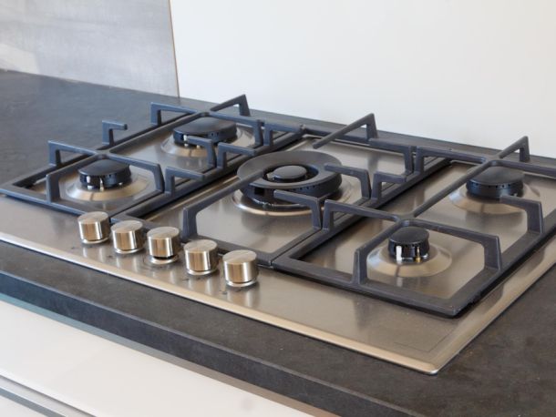 silver gas hob  with black grate on top  and it has 5 knobs