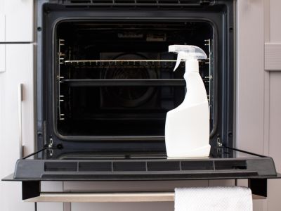 an opened oven door with a white spray bottle placed on the door
