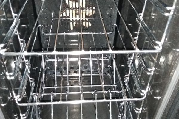 The oven is open and it is shiny clean, the oven light is on