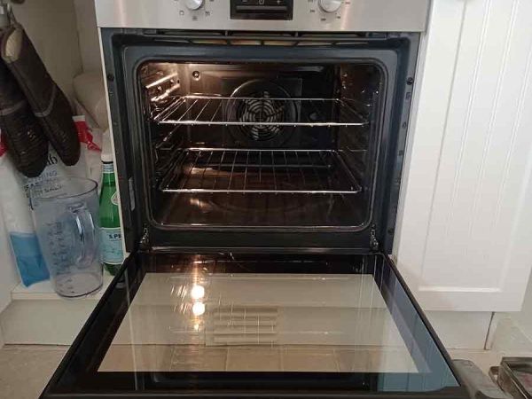 an oven with its door open, it is clean and the oven light is on
